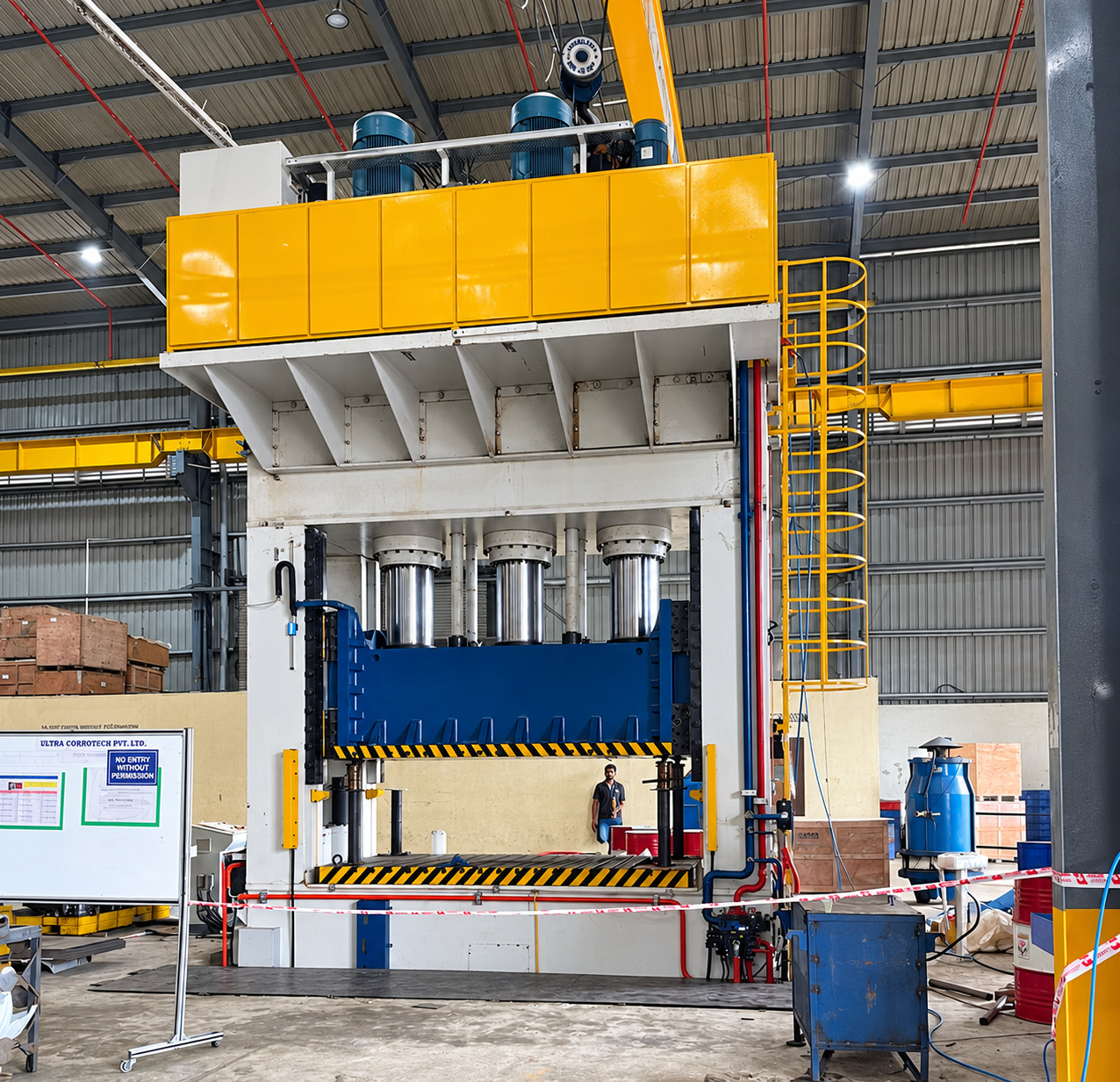 A tall four-column hydraulic press with a yellow crown and three large cylinders above a blue ram
